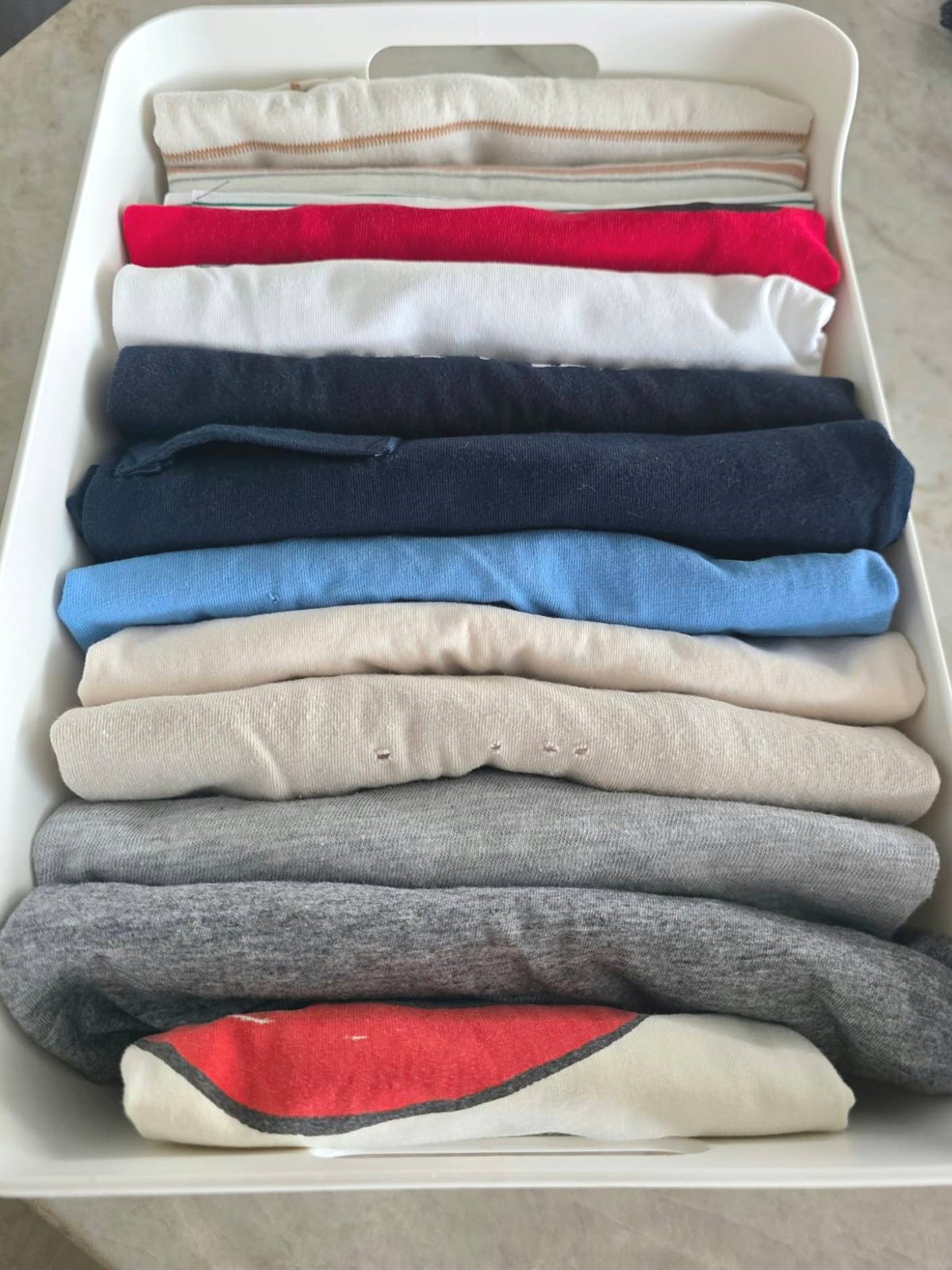 Cajón de camisetas dobladas de pie dentro de una bandeja